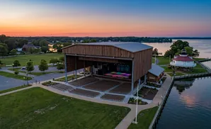 Outdoor amphitheater and lighthouse on a waterfront at sunset.