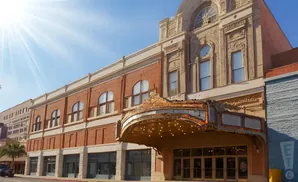 A historic theater with ornate marquee and brick facade under a bright, sunny sky.