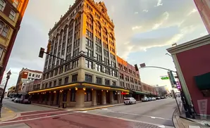 A street view of a grand, historic building with ornate architecture bathed in golden sunset light.
