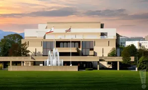 A modern building with a fountain in front and flags.