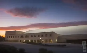 A modern building at dusk with colorful clouds in the sky.