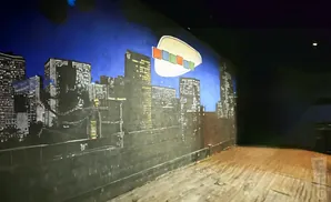A mural of a city skyline at night with a white oval shape containing colorful squares floating above.