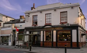 A pale building with a prominent lantern light stands on a street with a bus stop.
