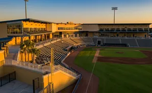 Baseball stadium with empty stands and a baseball field at sunset.