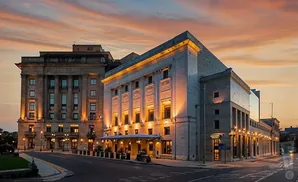 Grand buildings at sunset with ornate facades and warm lighting line a street.