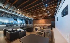 A modern bar with a long counter, stools, sofas, and tables.