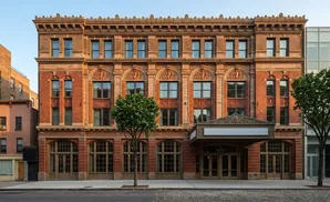 Exterior of a historic brick theater with ornate detailing and a modern glass building to the right.