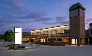 A lit building with a tower at dusk, featuring a large illuminated sign.