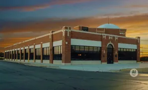 A brick building with a domed roof under a colorful sunset sky.