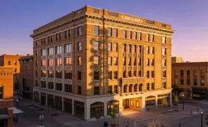 Exterior of a historic brick building with arched windows and decorative stonework, bathed in warm sunset light.