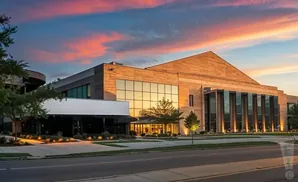 Modern building with wood and glass facade under a colorful sunset sky.