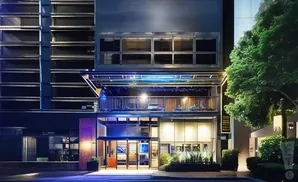 A modern building with glass doors and windows, illuminated at night.