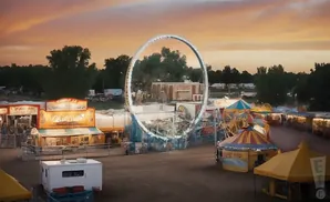 An amusement park at sunset, with rides and game booths.