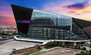 A modern, angular glass and dark-paneled building at sunset.