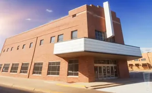 Red brick building with a prominent white structure on top, under a bright blue sky.