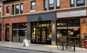 A brick building with storefronts, including a cafe and a shop with a 
