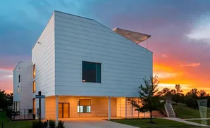 Modern white house with angular roof at sunset.