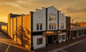 An old theater building bathed in golden sunset light, with brick accents and a marquis.