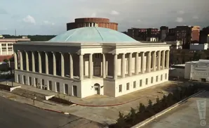 An aerial view of a large, white building with a domed roof and a colonnade.