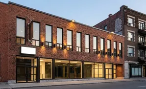Modern brick building with large windows and outdoor lighting.