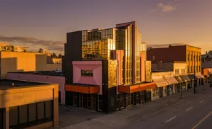 Art deco building with pink and glass facade, illuminated by golden sunset light.