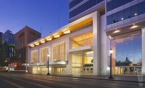 Modern glass building with large windows at dusk, reflecting the colorful sky.