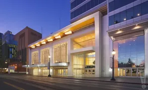 Modern building with large glass windows and illuminated facade at dusk.