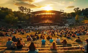 An outdoor amphitheater at sunset, packed with people watching a performance on stage.