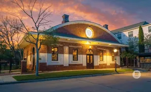 Sunset over a historic brick building with arched windows and a rounded roof.