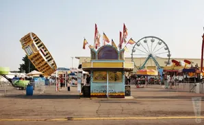 An amusement park with a Ferris wheel, rides, and food stalls under a clear sky.