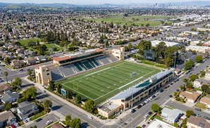 Aerial view of a football stadium surrounded by residential homes and businesses.