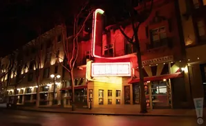 A vintage theater at night with a glowing marquee and neon lights.