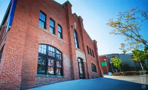 A red brick building with large black-framed windows under a bright blue sky.