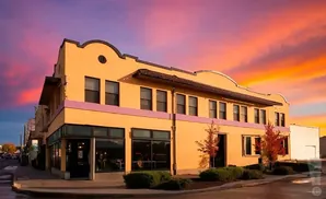 A yellow building with a pink stripe under a vibrant orange and purple sunset sky.