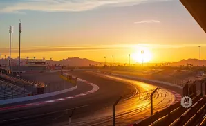 A racetrack bathed in golden sunset light, with mountains in the distance.