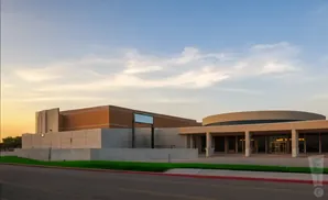 Modern building with a curved entrance under a clear sky at sunset.