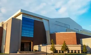 Modern brick and tan building with large blue glass windows under a bright blue sky.