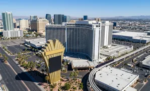 Aerial view of a large hotel and casino on the Las Vegas Strip with a monorail passing by.
