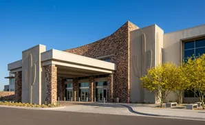 Modern building with cactus reliefs, stone accents, and yellow trees.