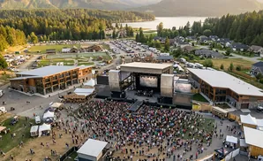 Aerial view of an outdoor concert with a large crowd gathered in front of a stage.