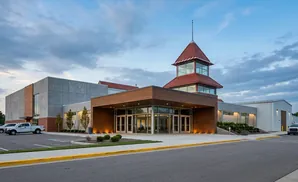 Modern building with a prominent red-roofed tower, wood accents, and large glass entrance.