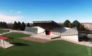 Modern outdoor amphitheater with a unique geometric design and red stage entrance.