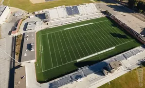 Aerial view of an empty football stadium with green turf field and bleachers.