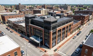 Aerial view of an urban intersection with brick buildings and parked cars.