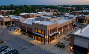 Aerial view of a modern commercial building with brick facades and large windows at dusk.