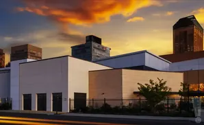 Modern buildings with a vibrant sunset sky and light streaks on the road.