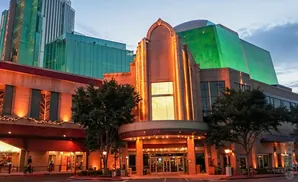 Exterior of a modern building with glass and stone facades, illuminated with warm orange lights at dusk.