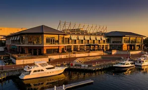 A modern waterfront building with boats docked at sunset.
