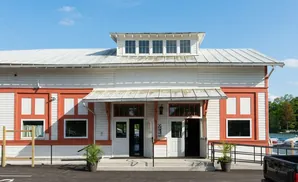 Exterior of a white building with red trim and a metal roof, featuring several windows and two open doors.