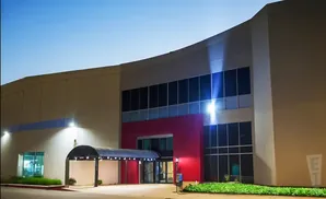 Modern building entrance at dusk with red accents and a covered walkway.